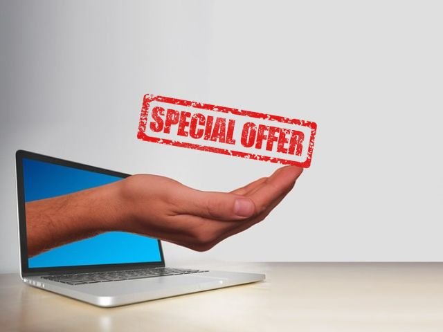 Hand ragt aus dem Notebook und hält den Hinweis Special Offer