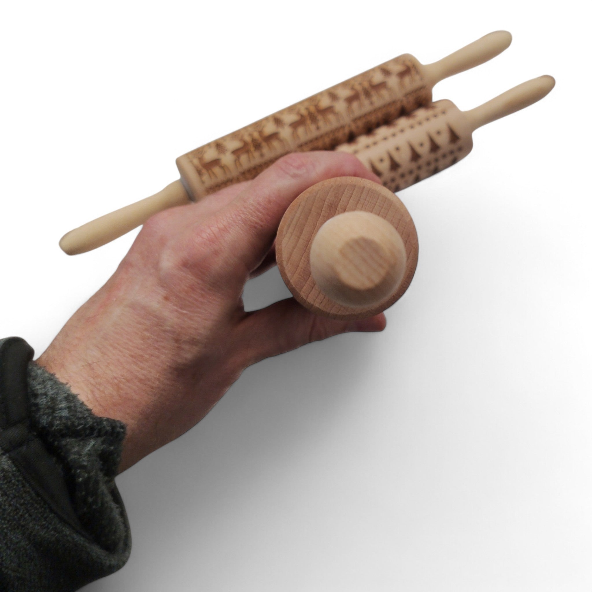 Eine Hand hält das KitchenCraft 3er Set Weihnachts-Nudelhölzer Keksroller Teigroller - drei hölzerne Nudelhölzer von KitchenCraft, ideal für festliches Backen - vor einem weißen Hintergrund.