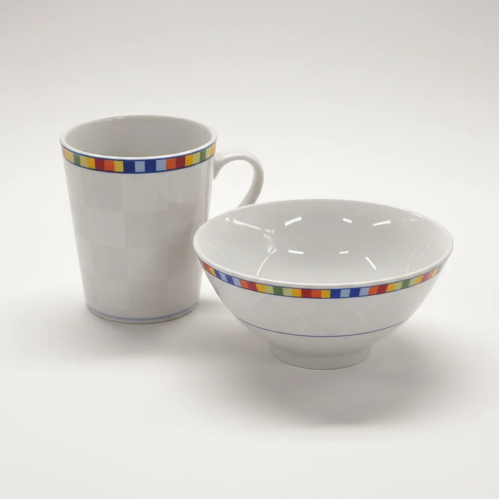 Das Venezia Kaffeebecher + Müslischüssel Bundleset von Fast Bundle, exklusiv bei Retourify, besteht aus weißen Keramikstücken mit bunten, quadratischen Randmustern, die von italienischem Design inspiriert sind und auf einem schlichten weißen Hintergrund abgebildet sind.