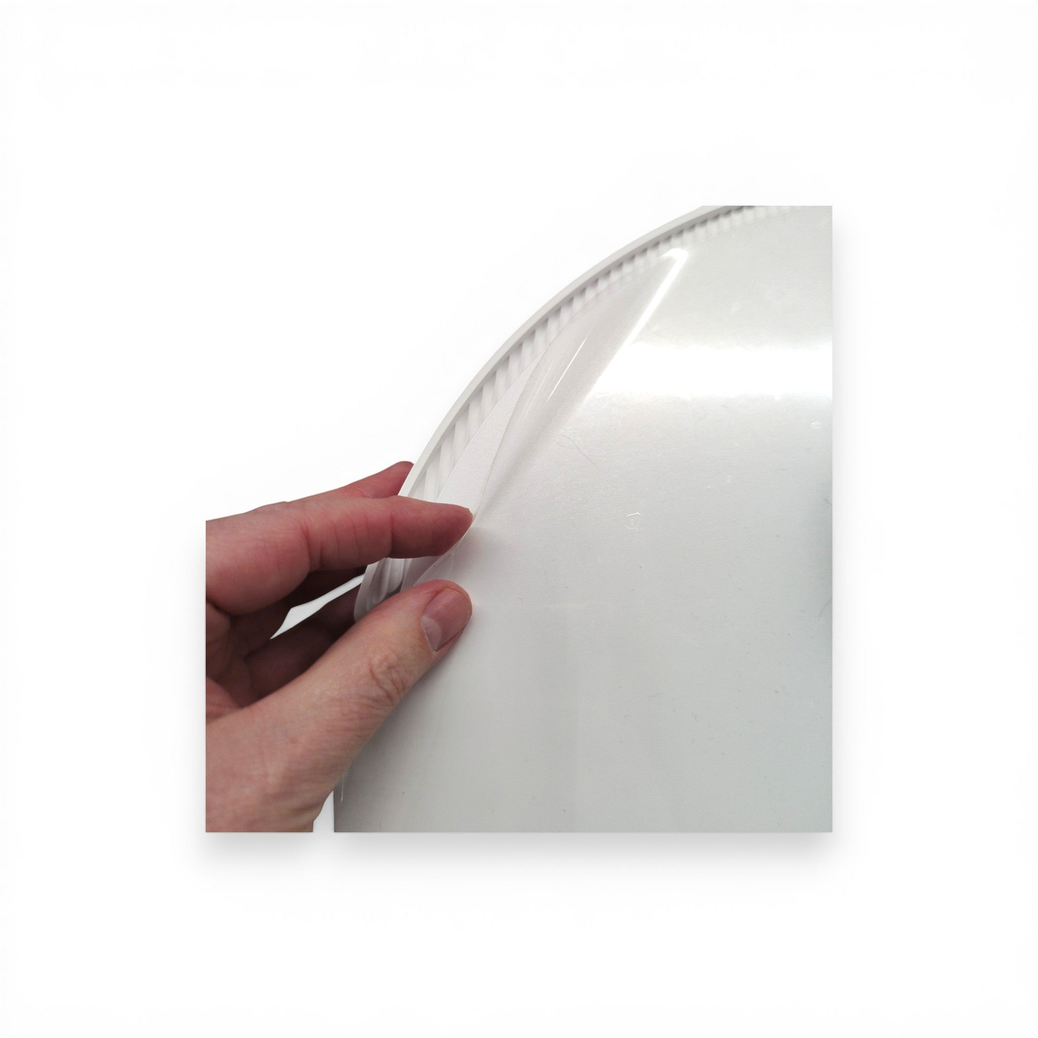 Hand zieht Schutzfolie von weißem Kunststoffartikel, Nahaufnahme, B-Ware Detail