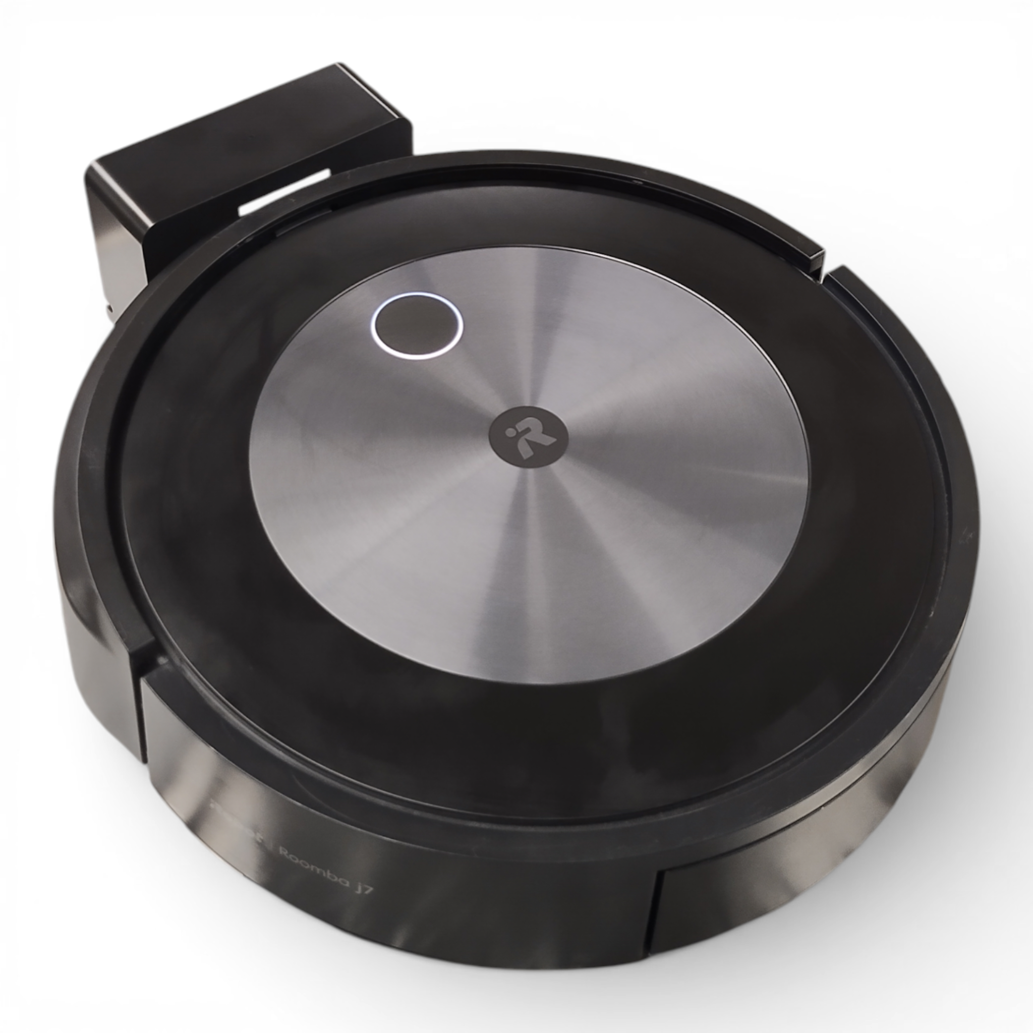 Ein runder, schwarzer iRobot Roomba J7+ (Mod. RVE-Y1) mit Metallkern ist an seiner Ladestation angedockt und zeigt den Komfort der App-Steuerung und Ein-Knopf-Bedienung dieses TOP gebraucht Modells.